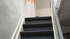 Una escalera con barandilla y una lámpara en la pared.