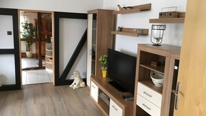 Un espacio habitable moderno con televisor, estanterías de madera, un perro y una escalera.