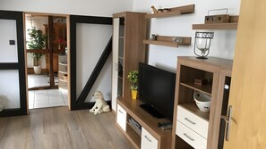 Un soggiorno moderno con televisione, scaffali in legno, un cane e una scala.