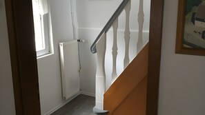 Una scala con balaustre bianche e corrimano in legno che conduce a un pianerottolo.