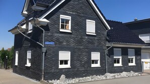 Una casa moderna negra con contraventanas blancas, cielo despejado y una señal de calle.