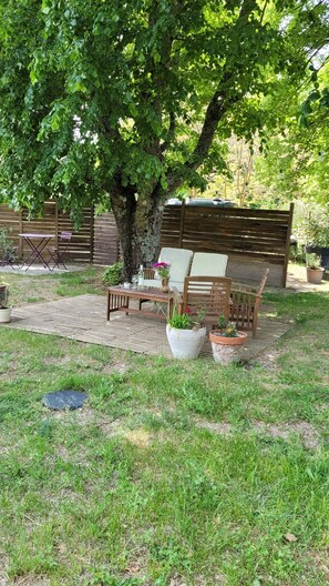 A wooden deck with outdoor furniture, a large tree, and potted plants. - A small house in the southern Luberon, surrounded by nature (Peypin-d'Aigues)