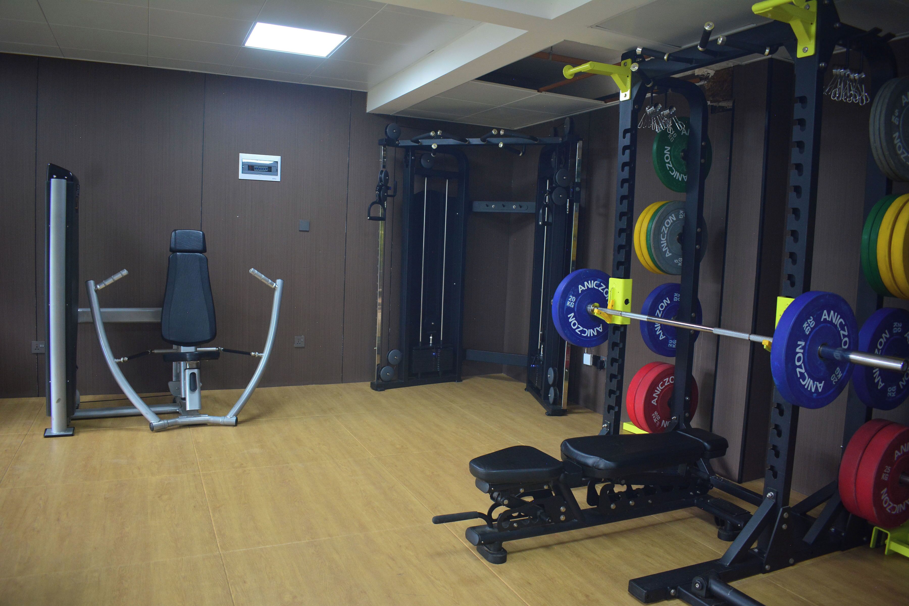 A gym with weightlifting equipment, benches, and a squat rack.