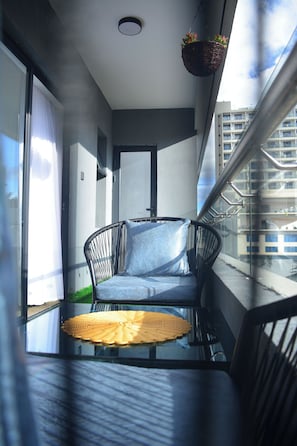 A balcony with a chair, a small table, and a hanging basket with plants. - Juliett Luxe Kilimani near Yaya (Nairobi)