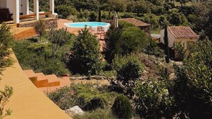 A villa with a swimming pool, surrounded by lush greenery and hills. - Exclusive Villa Serra de Baixo - Porto Covo (Setúbal)
