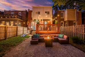 Ein Garten mit Feuerstelle, Sitzgelegenheiten und einer Holzterrasse.