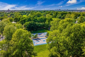 Vista aérea de un parque con canchas de baloncesto, rodeado de árboles verdes y frondosos.