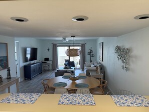 Un salon moderne comprenant un coin repas, un téléviseur fixé au mur et un ventilateur de plafond.