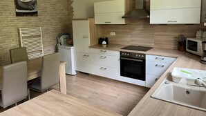 A modern kitchen with a brick wall, white cabinetry, a built-in oven, and a microwave.
