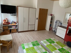 Ein Zimmer mit einem Bett, einem Schreibtisch, einem Kleiderschrank, einem Fernseher und einem Bücherregal.
