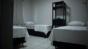 A room with three beds, a dark-colored shelf unit, and a white curtain. - Hostel Estação da XV (Telêmaco Borba)