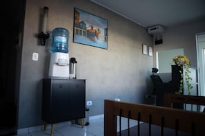 A room with a water dispenser, a painting, a desk, and a chair. - Hostel Estação da XV (Telêmaco Borba)