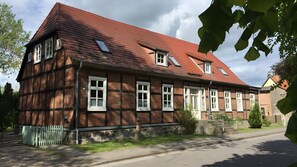 A traditional half-timbered building with multiple windows, a sloped roof, and a stone foundation. - Holiday Apartment for 5 People (55 m²) in Ivenack (Ivenack)