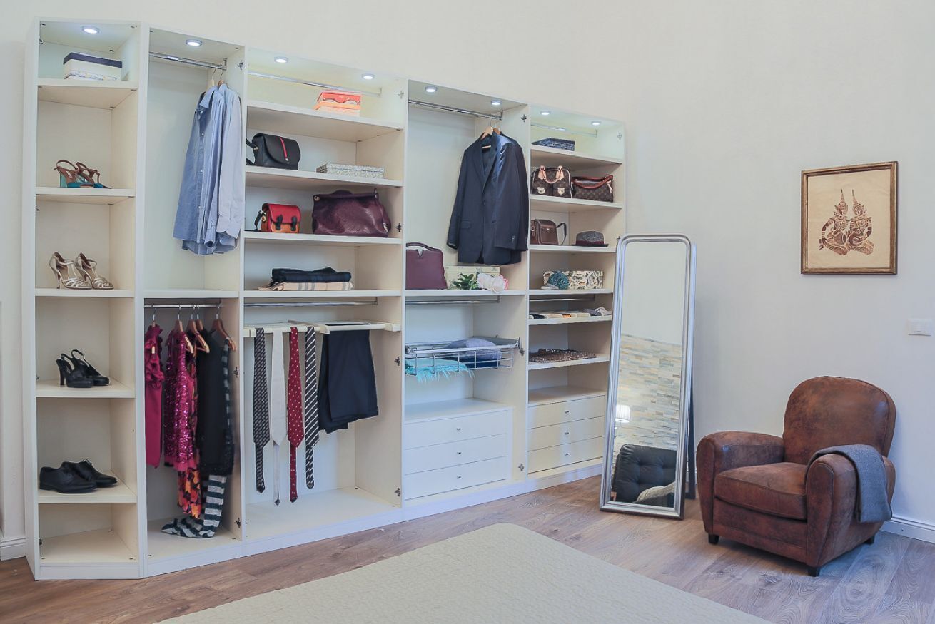 Een inloopkast met planken, lades en een kledingroede voor kleding en schoenen.