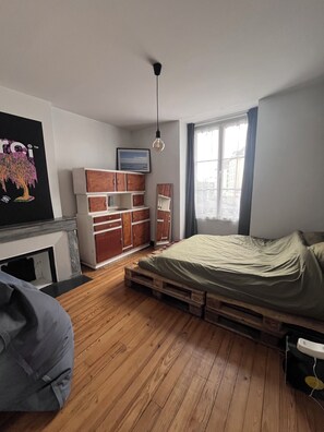 A bedroom with a bed, wooden flooring, a dresser, a painting, and a window. - Cosy apartment in historic center of Pau (Pau)