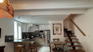 Un vaste espace de vie comprenant une cuisine, une table à manger et un escalier.
