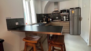 Une cuisine moderne dotée d’un îlot central, de tabourets de bar, d’un four à micro-ondes, d’une machine à café et d’un réfrigérateur.