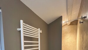 Une pièce avec un radiateur blanc, un plancher noir et un mur beige.