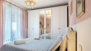Une chambre à coucher avec un lit, une armoire, un lustre et un miroir.