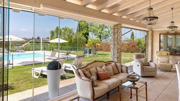 Un vaste espace de vie avec une grande fenêtre, une piscine et du mobilier d’extérieur.