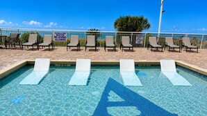 A shallow water pool with a diving sign, lounge chairs, and a clear blue sky. - Executive Pineapple Escape-Ocean View & Relaxation (Myrtle Beach)