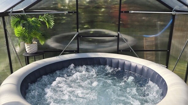 A hot tub inside a greenhouse with a potted plant and a view of trees outside. - La Tiny de Lili A moment out of time. (Draveil)