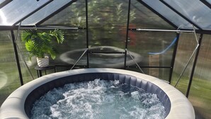 A hot tub inside a greenhouse structure with a potted plant on a table. - La Tiny de Lili A moment out of time. (Draveil)