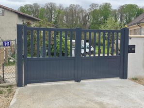 A gated entrance with a number sign, a concrete driveway, and a residential building in the background. - La Tiny de Lili A moment out of time. (Draveil)