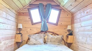 A cozy wooden room with a bed, two bedside lamps, a window with curtains, and a small shelf with a lamp and a plant. - La Tiny de Lili A moment out of time. (Draveil)