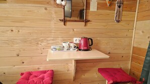 A wooden cabin interior with a table, two benches, a kettle, cups, and a small plant. - La Tiny de Lili A moment out of time. (Draveil)