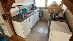 A compact kitchen with white cabinets, a washing machine, a toaster, and a window providing natural light. - Cozy attic apartment main station/city (Nürnberg)