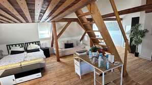 A loft bedroom with a wooden ceiling, a bed, a desk, and a sofa. - Cozy attic apartment main station/city (Nürnberg)