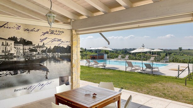A room with a view of a swimming pool, outdoor seating, and a mural. - Bardolino Golden Hill (Bardolino)