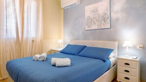 A bedroom with a bed, two bedside tables, a wall-mounted air conditioner, and a painting. - Bardolino Golden Hill (Bardolino)