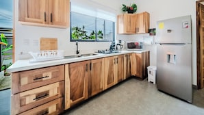 Una cocina moderna con armarios de madera, un refrigerador de acero inoxidable, un microondas y un lavamanos.