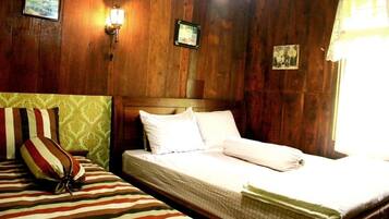 A room with wooden panel walls, a bed with white bedding, striped pillows, and a small bedside table.