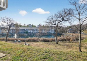 A lakeside view with a building in the background, trees, and a grassy area. - Quiet 2bd room condo with beautiful scenery in the heart of Branson (Branson)