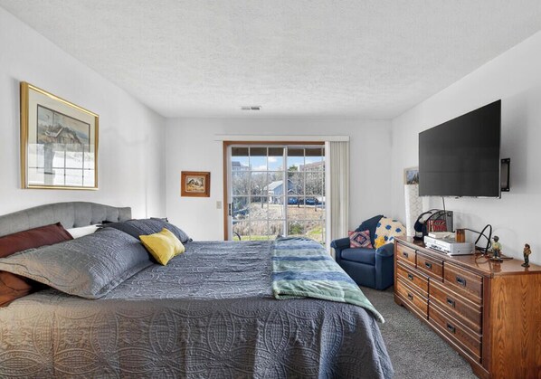 Une chambre à coucher avec un lit, une commode, un téléviseur et une fenêtre donnant sur un beau paysage.