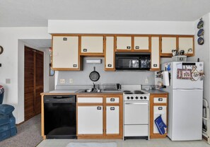 Une cuisine de taille réduite, dotée de meubles en bois, d’un four à micro-ondes, d’une cuisinière et d’un réfrigérateur.