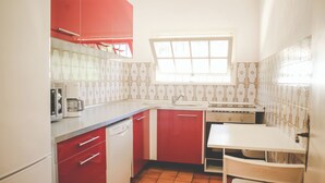 A kitchen with red cabinets, a white countertop, a window, and a tiled backsplash. - Antheor Fairy Sea View 2 rooms in Villa (Saint-Raphaël)