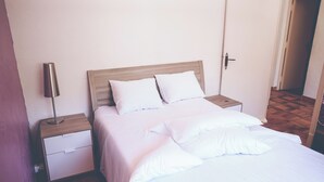 A neatly made bed with white bedding and pillows, a wooden headboard, a bedside table with a lamp, and a nightstand with a drawer. - Antheor Fairy Sea View 2 rooms in Villa (Saint-Raphaël)