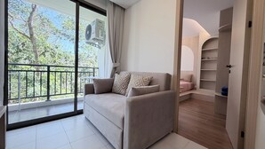 Un soggiorno moderno con divano, un balcone con vista sugli alberi e una cabina armadio.