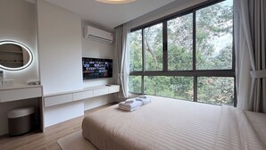 Una camera d'hotel con un letto grande, una TV fissata alla parete, una scrivania con uno specchio e una finestra con tende.