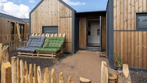 Eine Holzhütte mit Schlafpodest und kleiner Sitzgelegenheit im Freien.