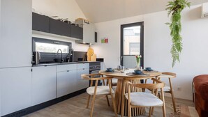 Eine moderne Küche mit grauen Schränken, einem Holztisch mit Stühlen und einer hängenden Pflanze.