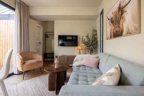 Ein Wohnzimmer mit einer Couch, einem Sessel, einem Couchtisch und einem Fernseher.