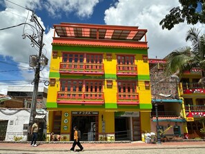 A multi-story building with balconies, a ground-level entrance, and a visible sign for a pharmacy. - Apartamento con Jacuzzi Parque Guatape Antioquia (Guatape)