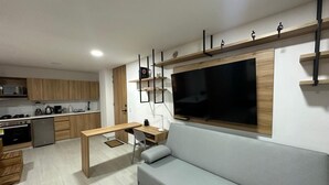 A modern kitchen with wooden cabinets, a dining table, and a built-in TV. - Apartamento con Jacuzzi Parque Guatape Antioquia (Guatape)