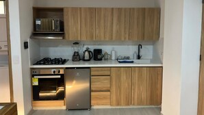 A compact kitchen with built-in appliances, a microwave, a stove, a coffee maker, and a sink. - Apartamento con Jacuzzi Parque Guatape Antioquia (Guatape)