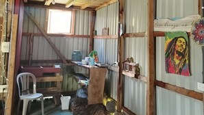 A rustic room with a wooden ceiling, a desk with a chair, a small table, and a wall with a poster. - Hippie Hut, Yoga and Relaxation (Paraiso)